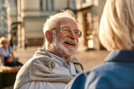 Älterer Mann lächelt in die Kamera und trägt dabei eine Brille